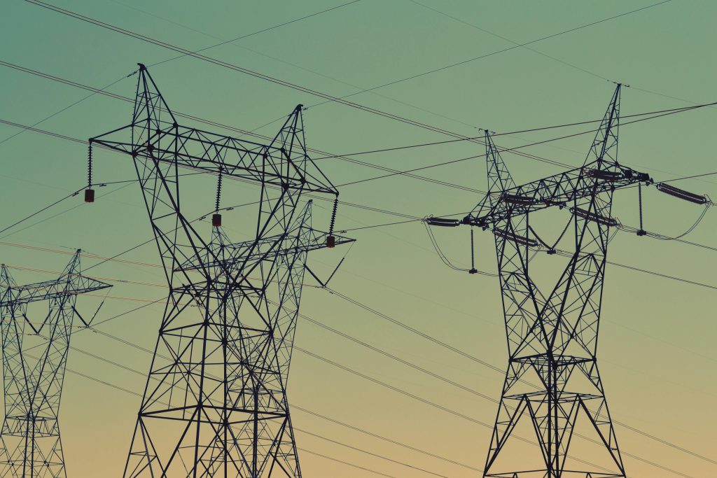 Silhouette of high voltage power lines against a twilight sky, illustrating energy infrastructure.